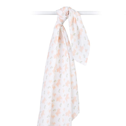 Cotton muslin swaddle draped over a rod, highlighting its airy weave and delicate pig and floral print.