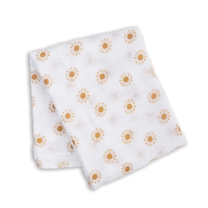 Folded muslin swaddle featuring a repeating print of mustard-yellow suns on lightweight white cotton fabric.