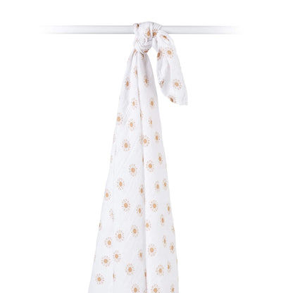 Cotton muslin swaddle draped over a rod, showing airy weave and cheerful sun pattern in earthy tones.