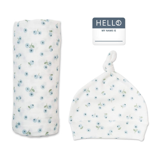 Lulujo Hello World set featuring soft white muslin swaddle with delicate blue floral pattern, matching knotted hat and personalized name tag for newborns.