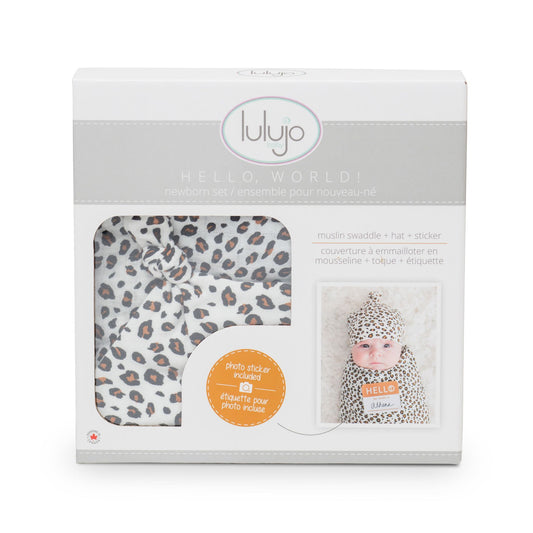 Lulujo Hello World gift box packaging showcasing leopard print swaddle set with muslin blanket, hat and personalized photo sticker included.