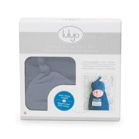 Lulujo Hello World gift box showcasing navy blue swaddle set with muslin blanket, knotted hat and photo sticker featuring baby Mitchell for birth announcements.