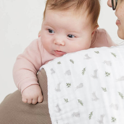 Baby resting on adult’s shoulder with Lulujo muslin burp cloth in bunny and fern print—soft, absorbent, and gentle on baby’s delicate skin.