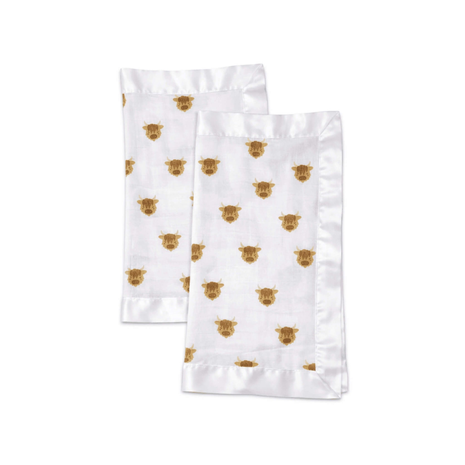 A pair of folded muslin security blankets in white fabric with brown highland cow print and smooth satin borders.