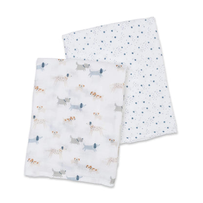 Two cotton muslin swaddles laid flat, one featuring small blue stars and the other with grey and tan dog illustrations.