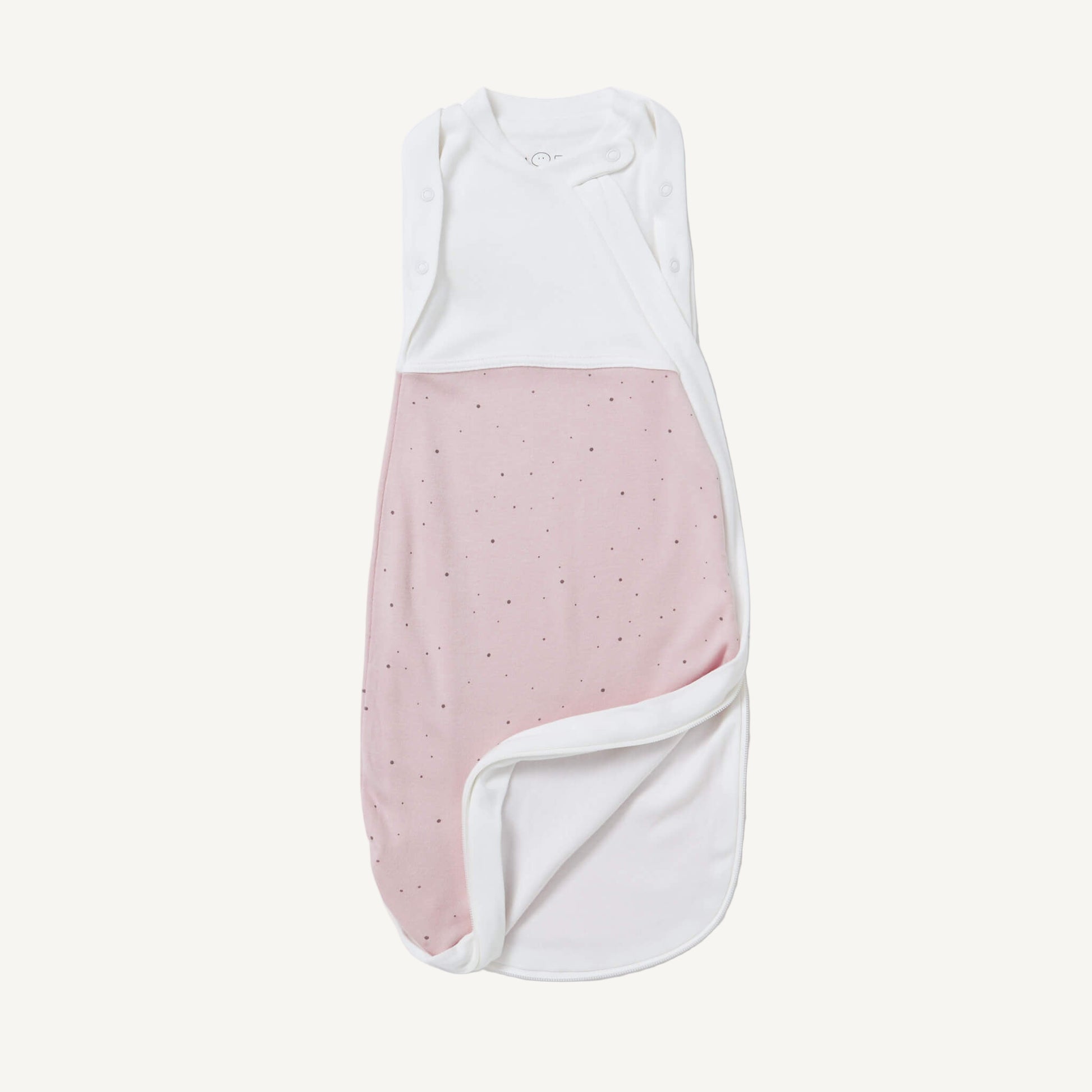 A soft pink newborn swaddle bag with scattered tiny dots is shown partly unzipped at the bottom to reveal the smooth white interior fabric.