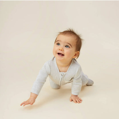 A baby crawling on a light surface while wearing a grey sleepsuit with a long front zip and long sleeves.