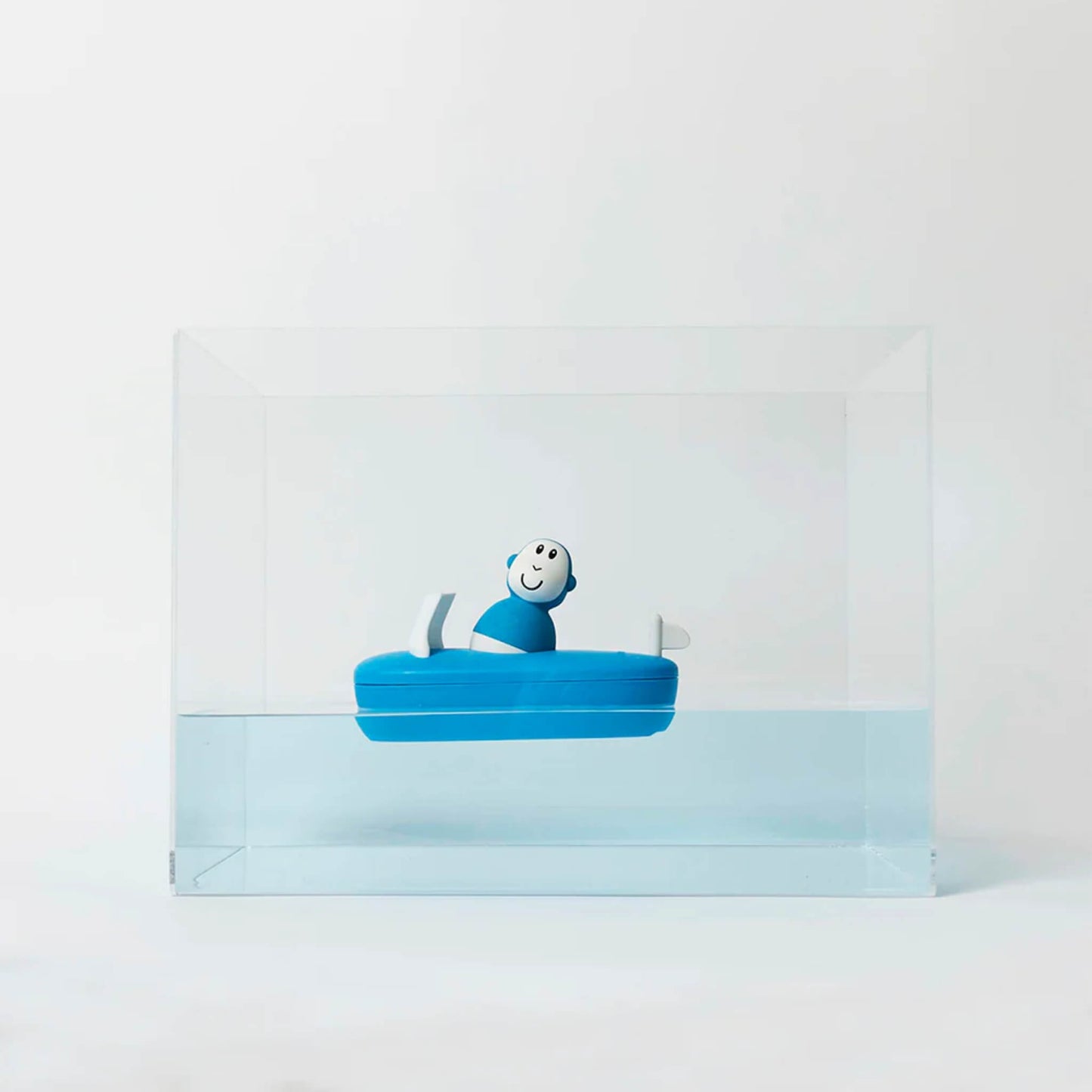 Blue bath boat toy floating in a clear water tank, showing the monkey figure sitting on top of the boat.