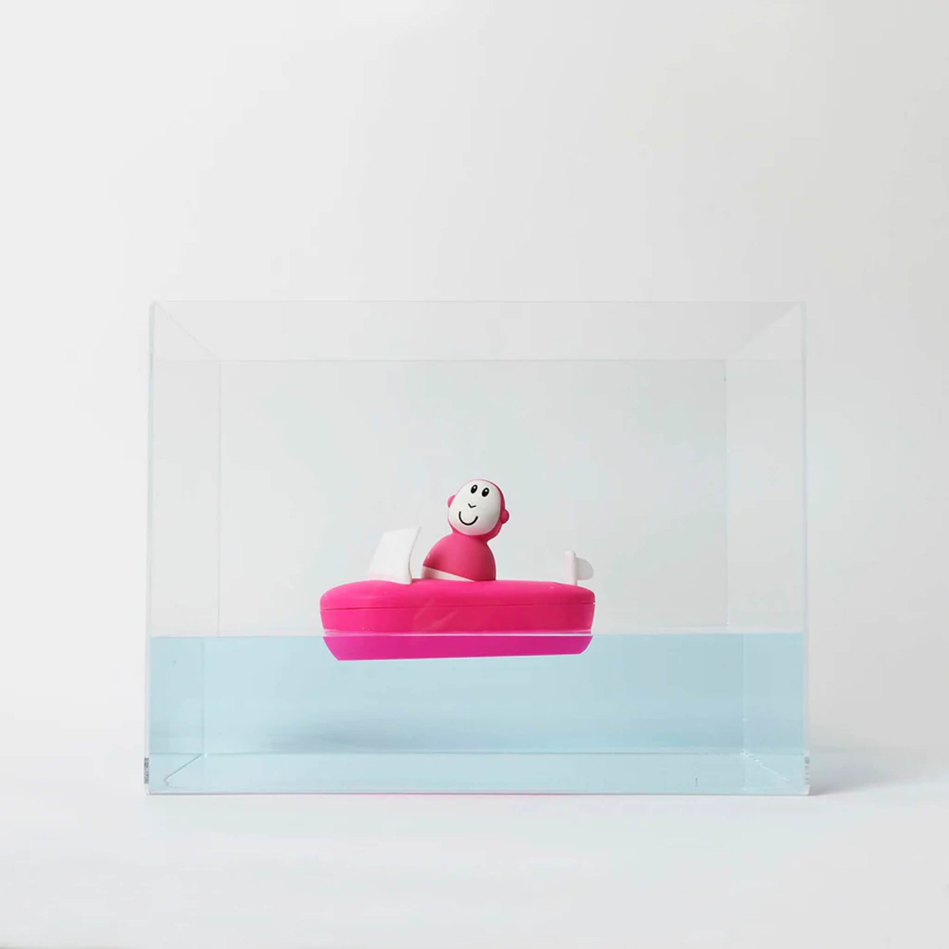 Pink bath boat floating in a clear tank of water, showing how the silicone base stays buoyant and level.
