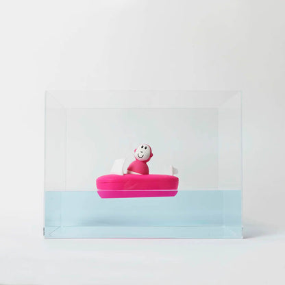 Pink bath boat floating in a clear tank of water, showing how the silicone base stays buoyant and level.