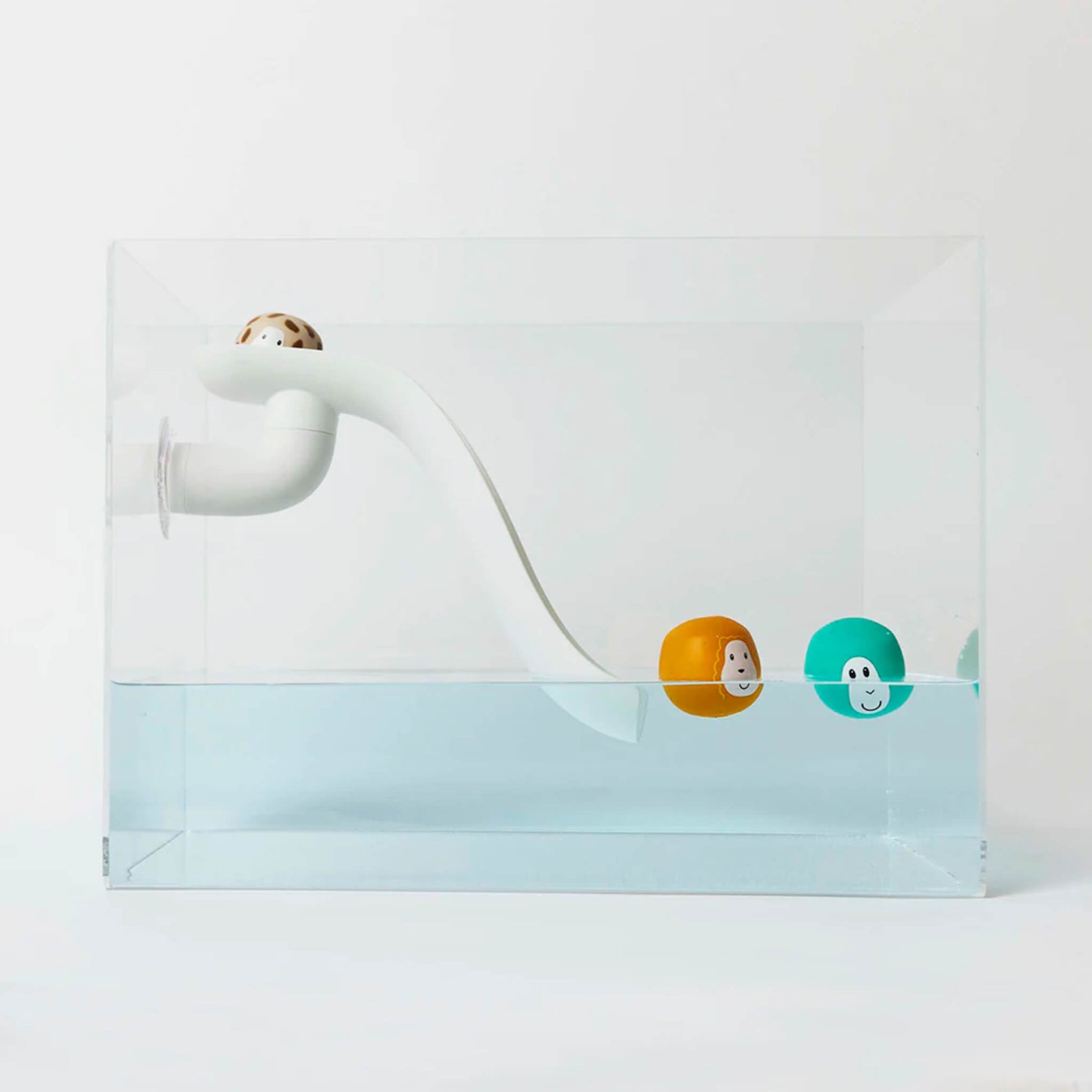 Whit curved slide bath toy positioned inside a clear water tank with three floating animal character balls resting near the slide in the water.
