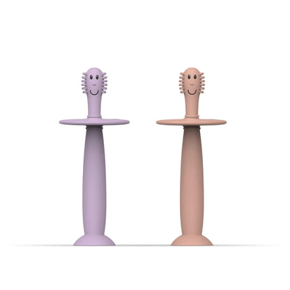 Matchstick Monkey Training Toothbrush with Stopper baby toothbrush set in dusty pink and lilac silicone with wide safety guards and suction cup bases.