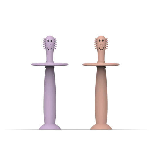 Matchstick Monkey Training Toothbrush with Stopper baby toothbrush set in dusty pink and lilac silicone with wide safety guards and suction cup bases.