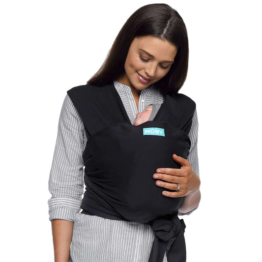 A mother wearing the Moby Classic Baby Wrap in black, holding her newborn securely against her chest.