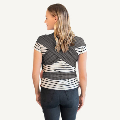 Back view of an adult wearing a grey houndstooth-patterned wrap with the fabric crossed over the shoulders and tied around the waist.