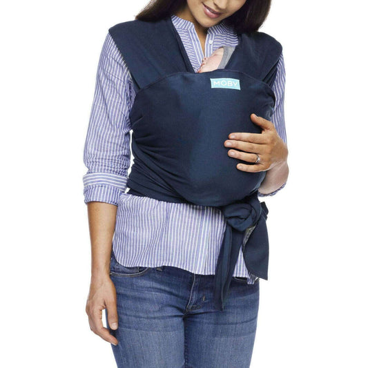 A mother wearing the Moby Classic Baby Wrap in Midnight navy, holding her baby close against her chest.