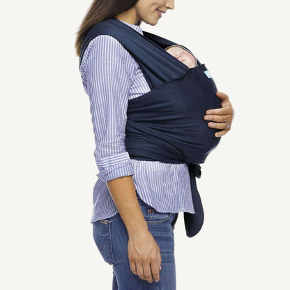 Side view of mother carrying her sleeping baby in a Midnight navy wrap carrier.