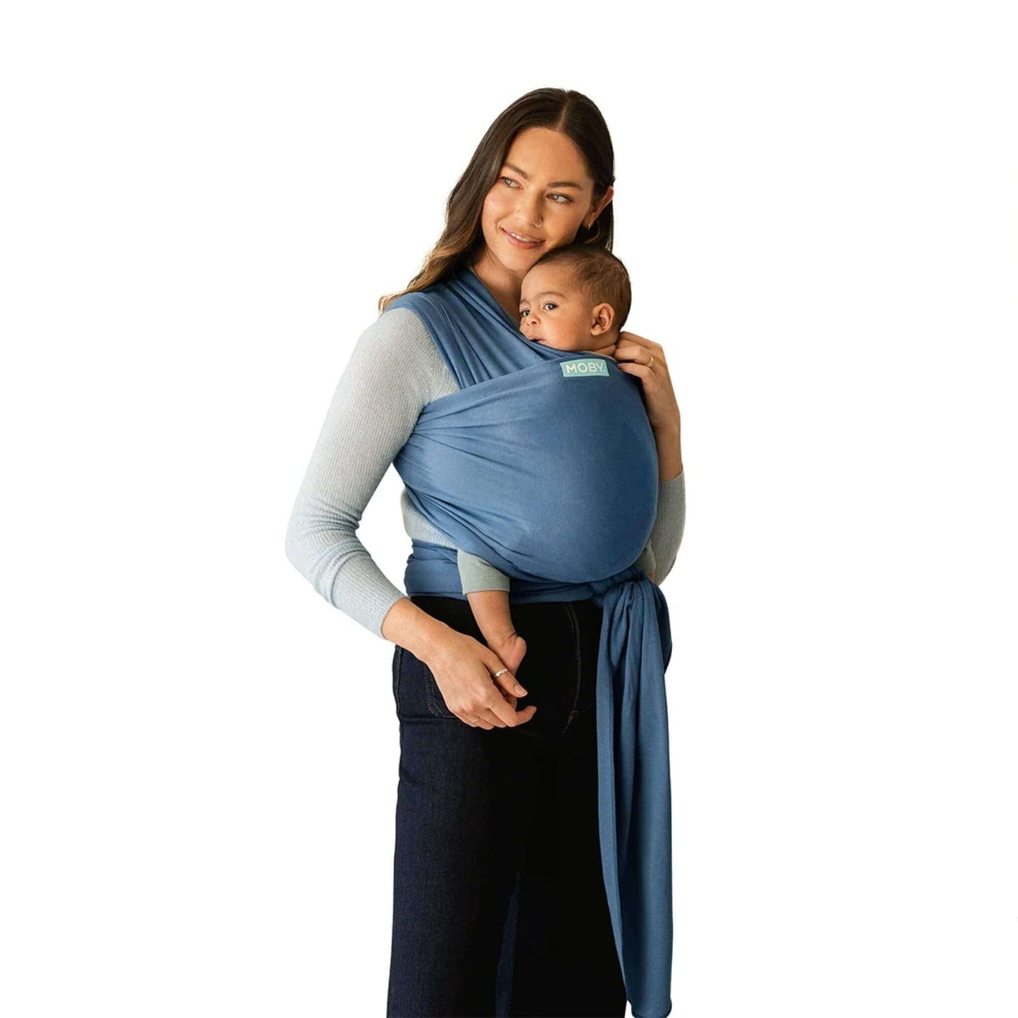A mother wearing the Moby Classic Baby Wrap in Ocean blue, holding her baby securely against her chest.