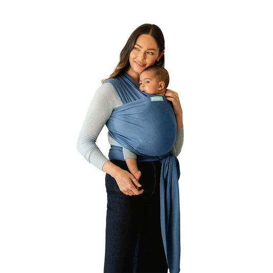 A mother wearing the Moby Classic Baby Wrap in Ocean blue, holding her baby securely against her chest.
