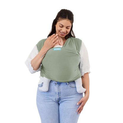 A mother wearing the Moby Classic Baby Wrap in Pear green, holding her baby close against her chest.