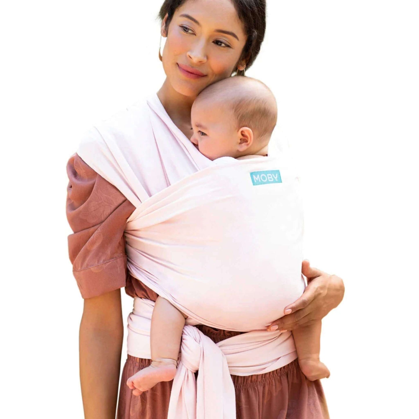 A mother wearing the Moby Classic Baby Wrap in Rose Quartz pink, holding her baby close against her chest.
