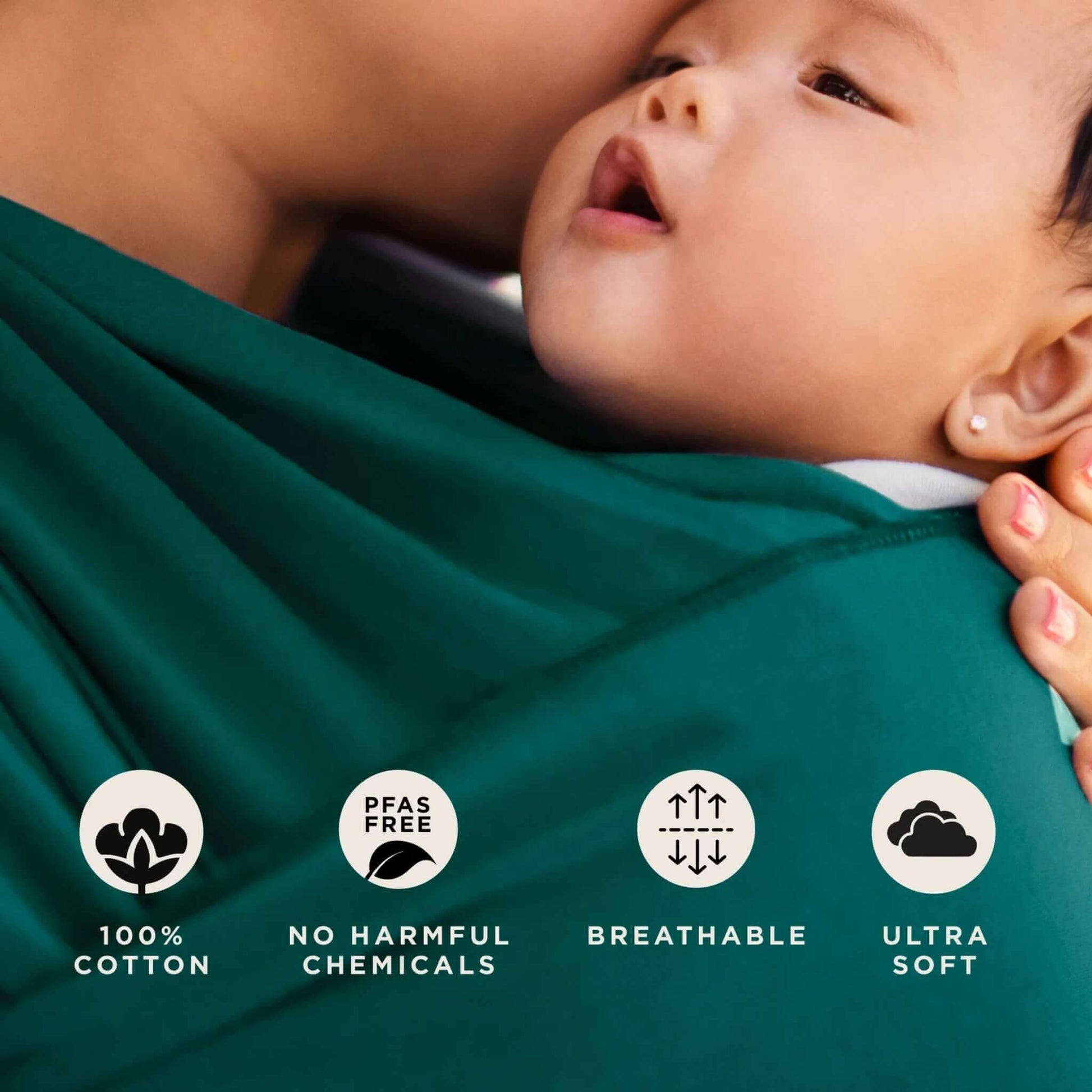 Close-up of baby resting in Pacific green wrap fabric beside icons for 100% cotton, PFAS free, breathable and ultra-soft qualities.