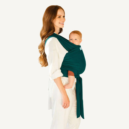 Mother wearing a white outfit carrying baby in a Pacific green wrap carrier with a secure front tie.