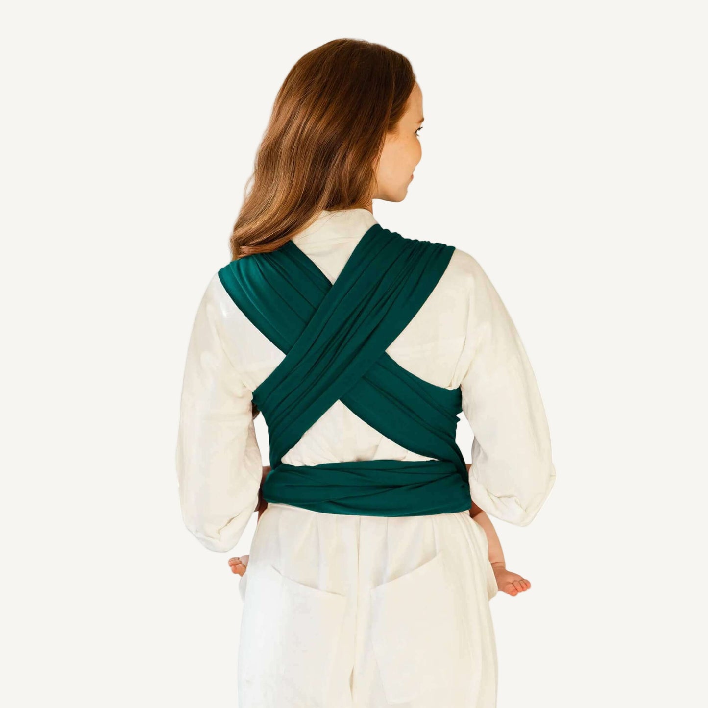 Back view showing cross-over straps and tied ends of a Pacific green baby wrap worn over a white outfit.