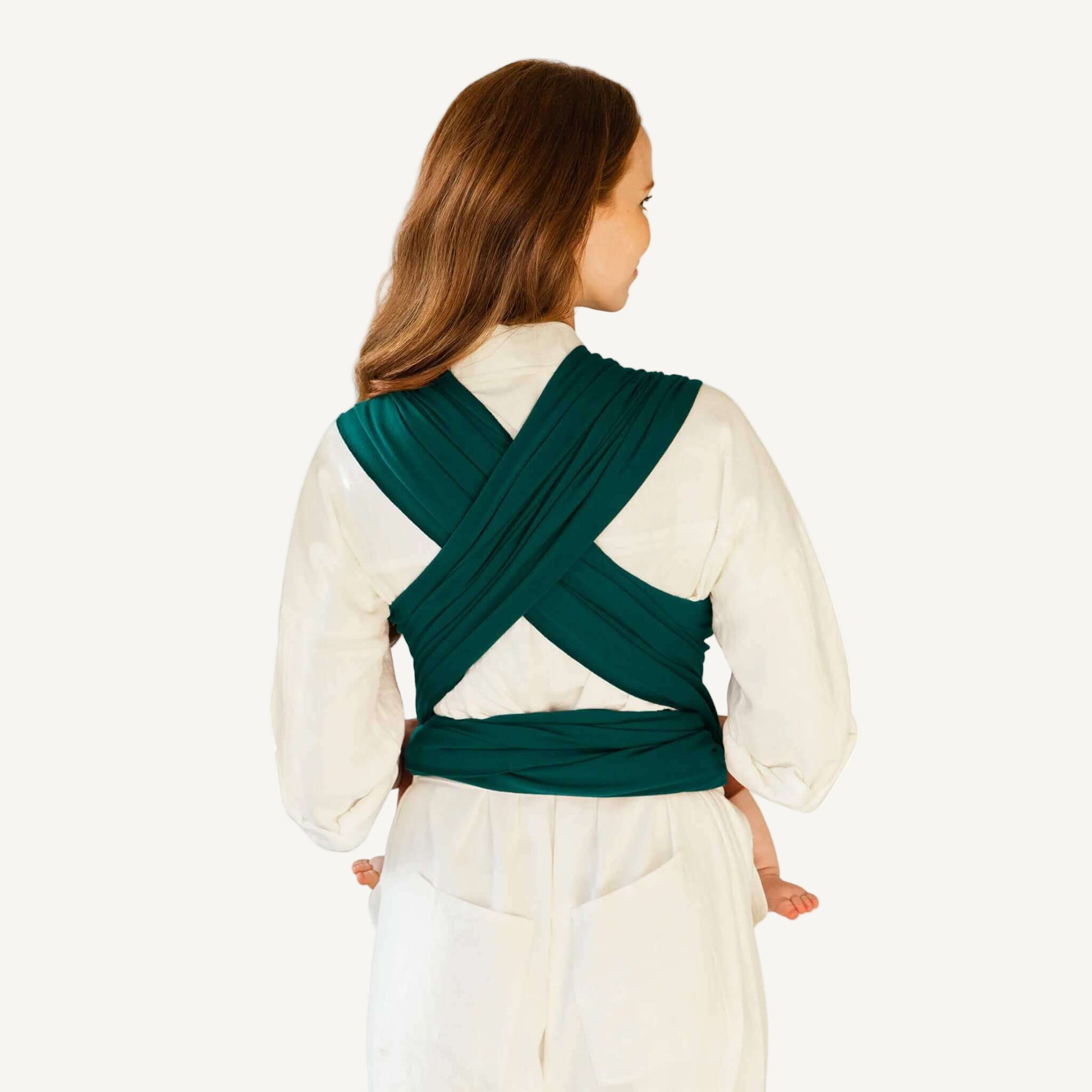 Back view showing cross-over straps and tied ends of a Pacific green baby wrap worn over a white outfit.