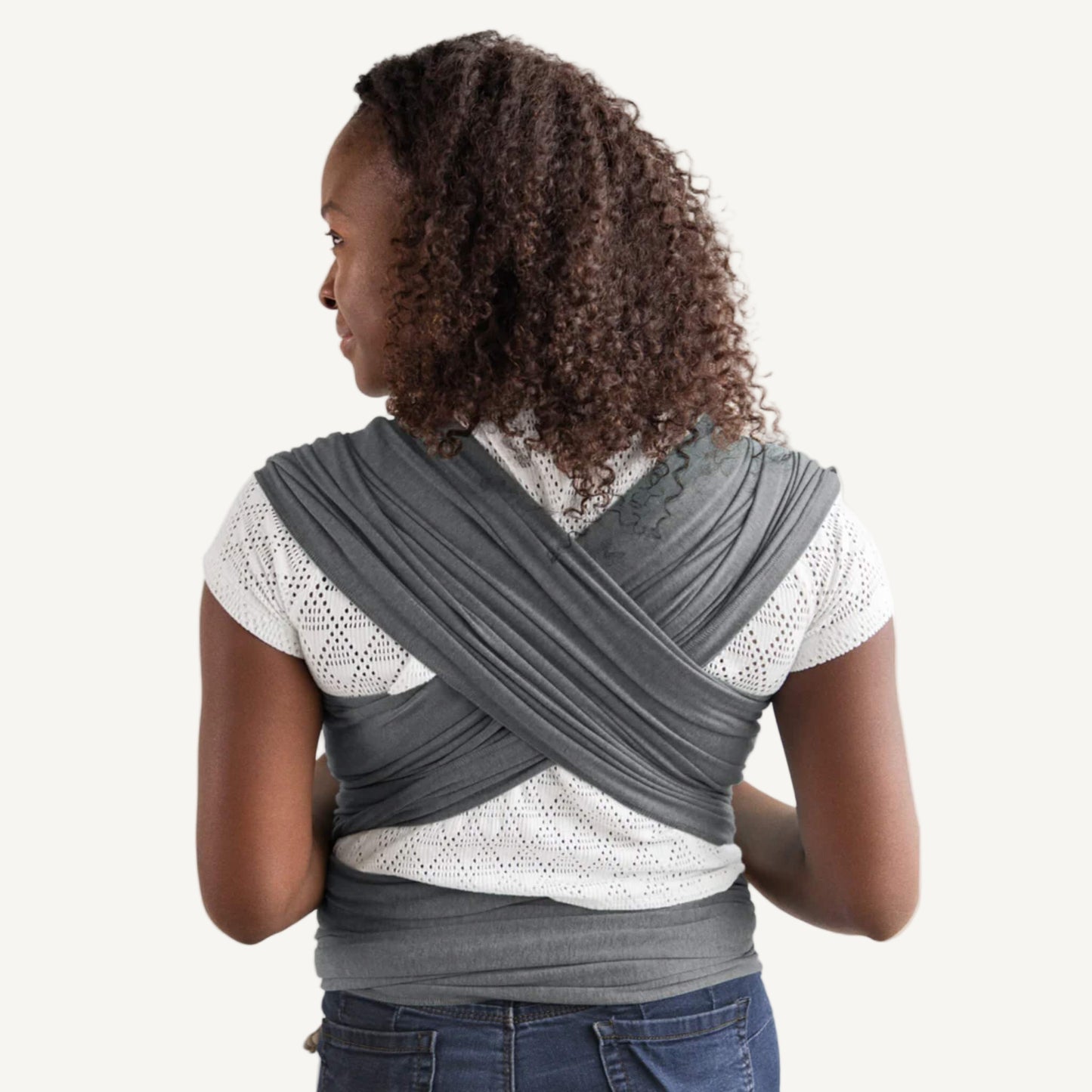 Deep grey wrap fabric crossed across a parent’s back, with wide layers spread evenly over the shoulders and tied around the waist.
