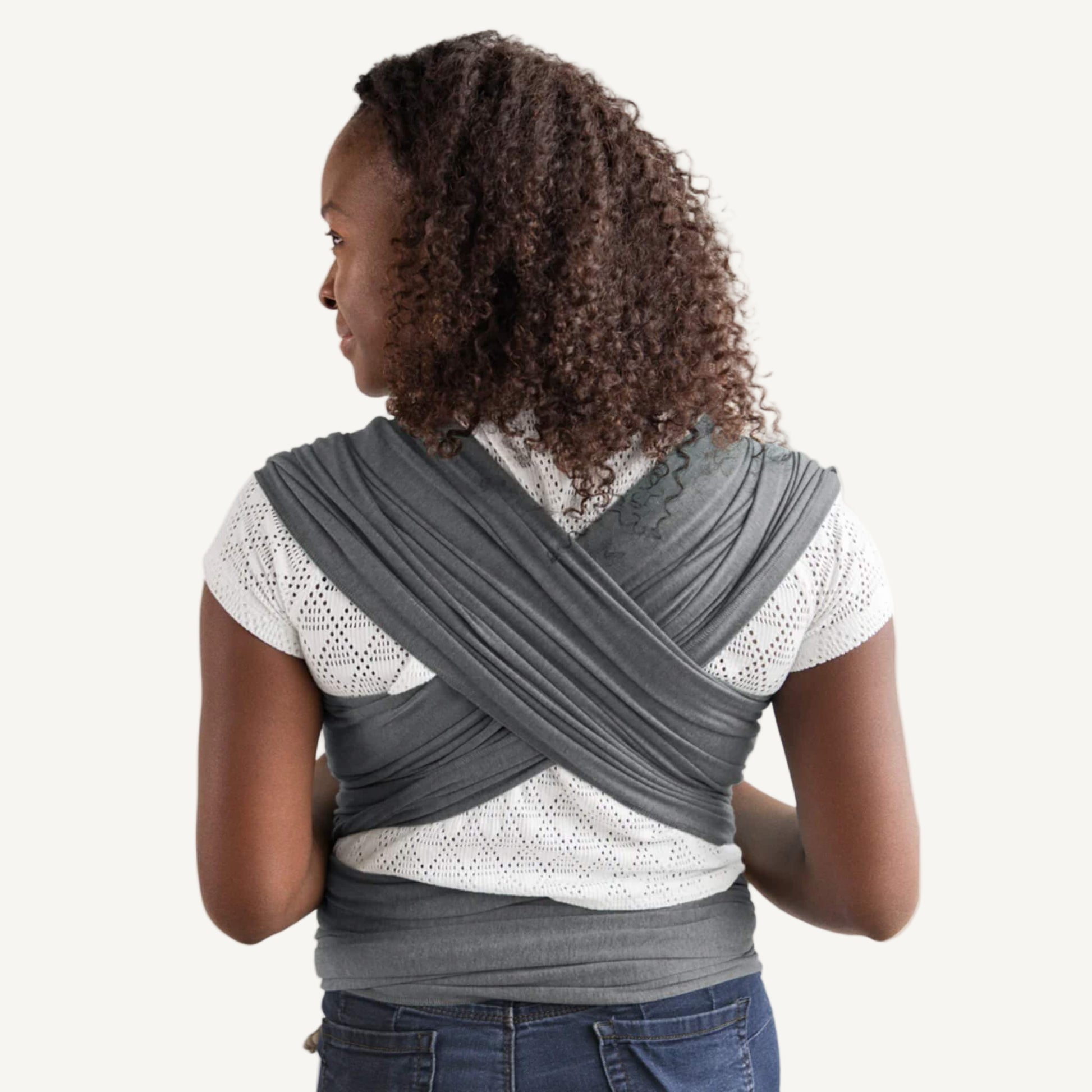 Deep grey wrap fabric crossed across a parent’s back, with wide layers spread evenly over the shoulders and tied around the waist.