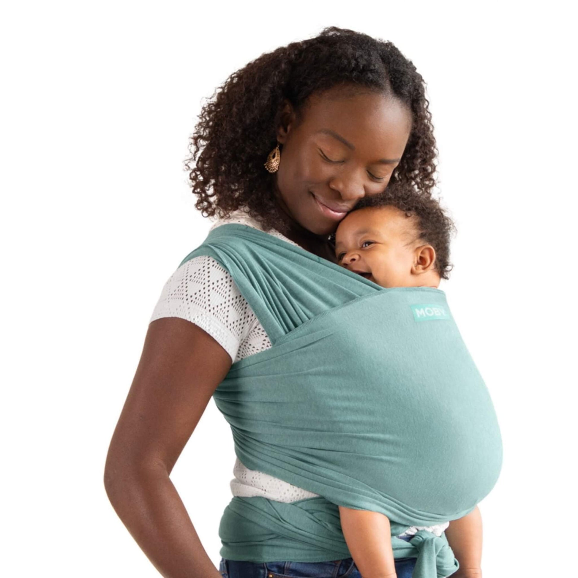 Parent standing in a front-carry position with a baby resting against their chest inside a soft teal wrap tied securely around the body.