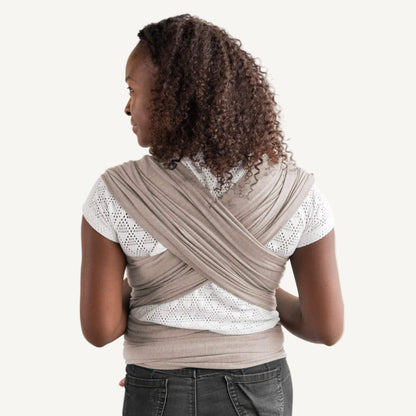 Criss-crossed baby wrap fabric shown across a parent’s back, with wide, evenly spread panels providing support and weight distribution.