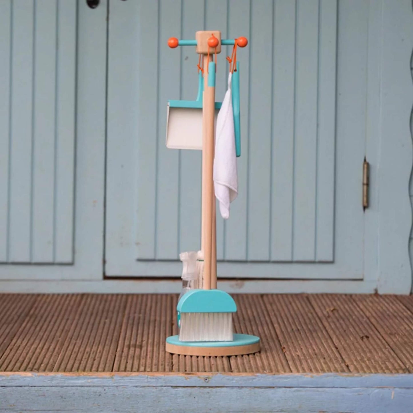 Moover Cleaning Set in blue placed on a porch, positioned neatly in front of a pale blue wooden door.