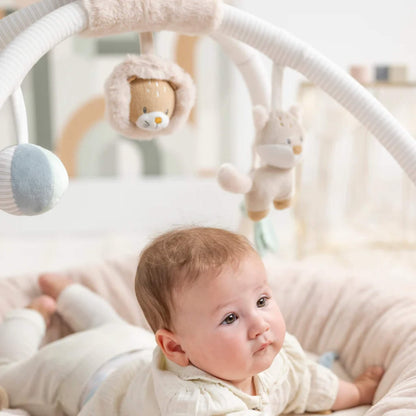 Close-up of three soft hanging animal toys and fabric shapes attached to a white arch above a padded baby play space.