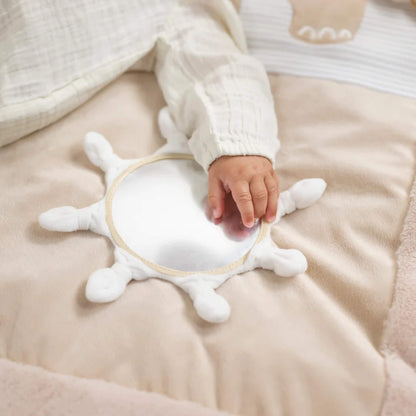 Small hand touching round baby-safe mirror sewn into cushioned playmat surface for sensory exploration.