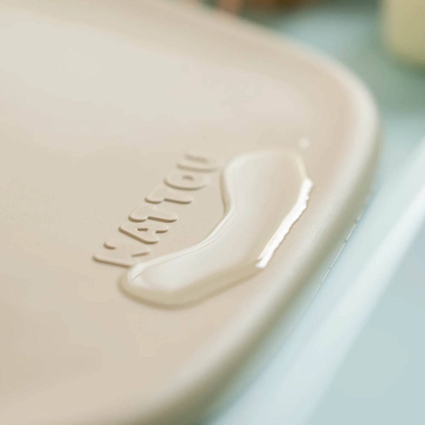Close-up of a small pool of water on the corner of a beige changing pad, showing its water-resistant surface.