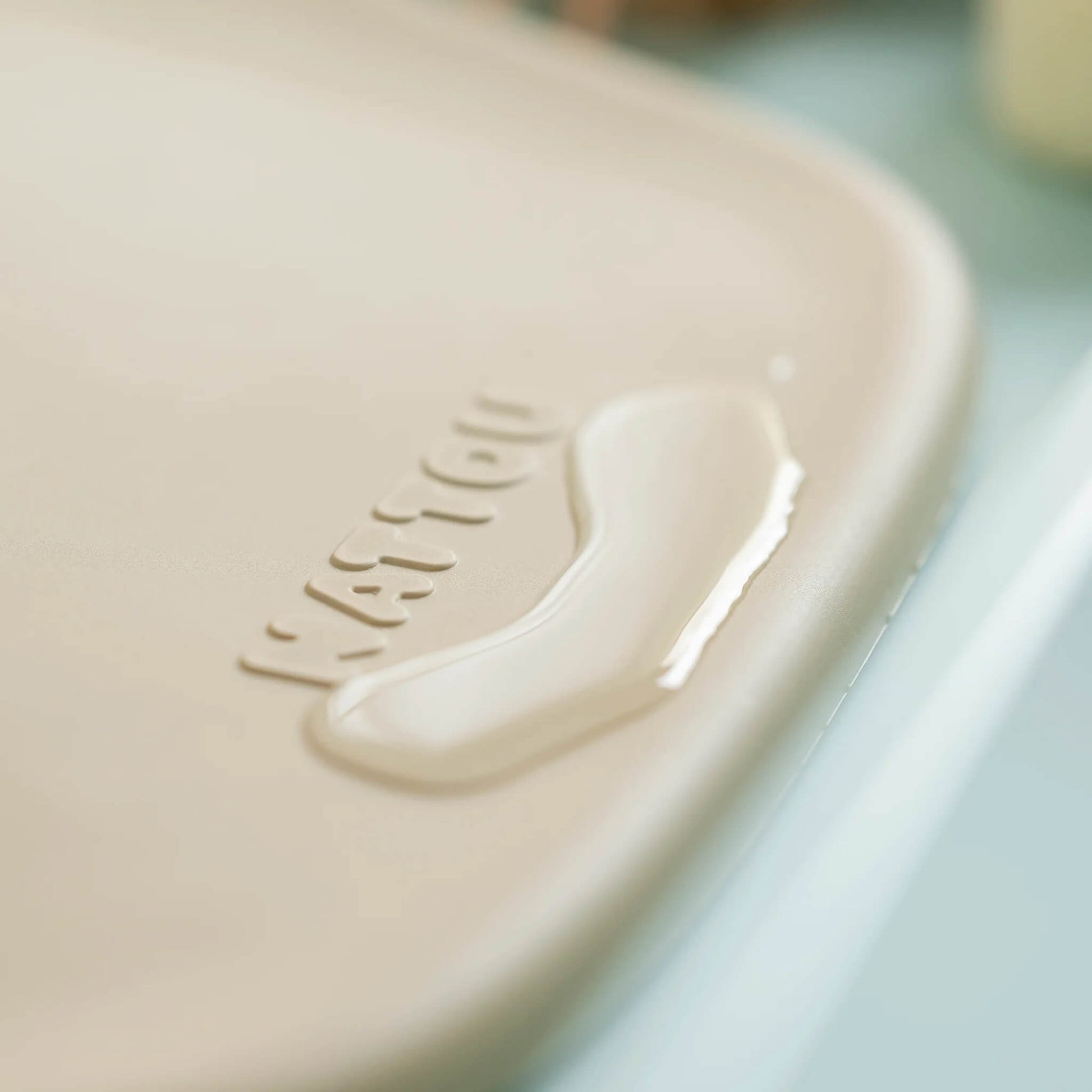 Close-up of a small pool of water on the corner of a beige changing pad, showing its water-resistant surface.