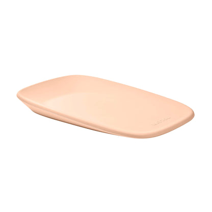 A peach changing pad photographed at a slight angle, highlighting the soft contour and embossed brand name.