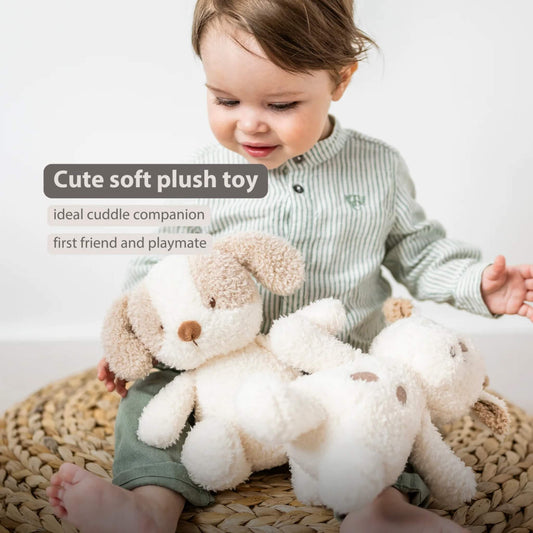 A small child sitting on a woven mat while holding a fluffy dog soft toy, with another similar toy resting beside them.