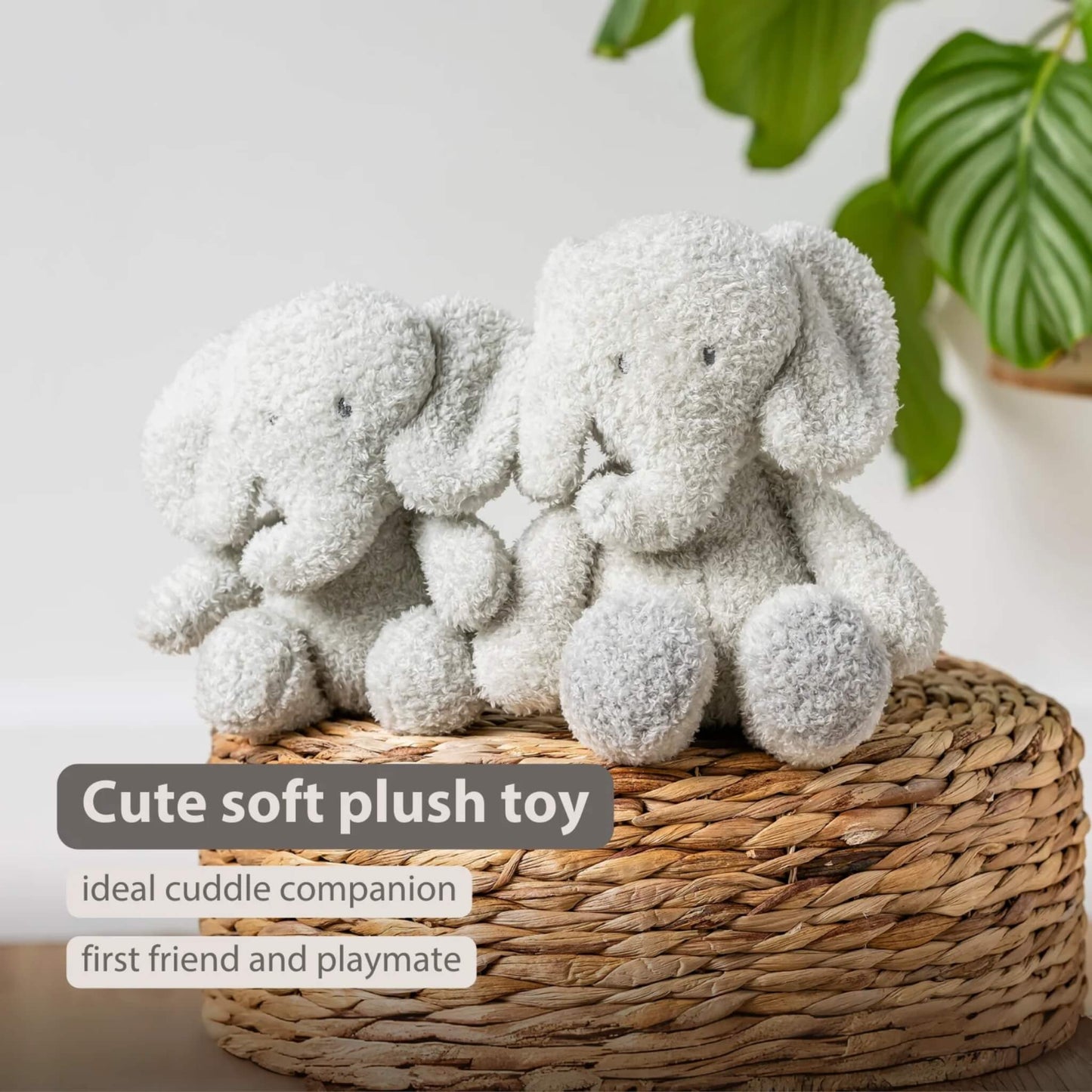 A pair of soft plush elephant toys sitting on a woven basket, both facing forward with rounded limbs and textured fur. The words “Cute soft plush toy”, “ideal cuddle companion” and “first friend and playmate” appear on the image.