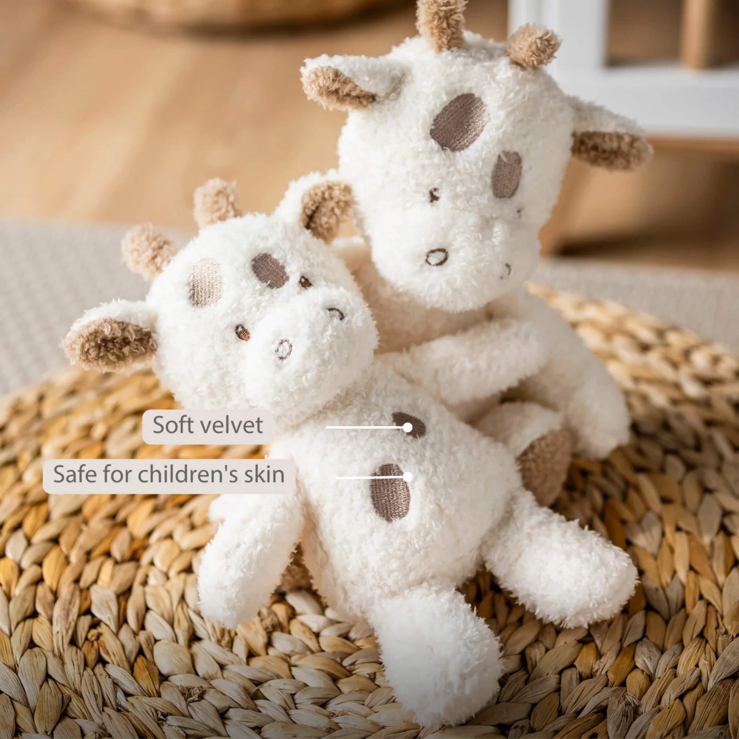 Two cream giraffe plush toys resting against each other on a woven basket, with visible embroidered spots and small horns, accompanied by on-image text reading “Soft velvet” and “Safe for children’s skin.”