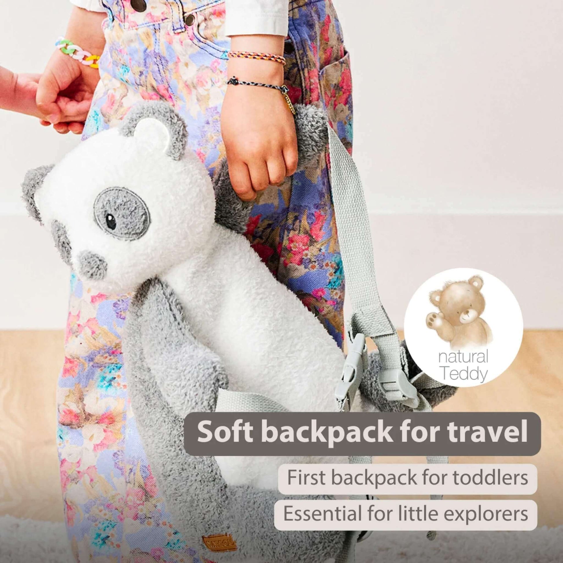 A toddler holding a panda-shaped backpack during a day out, showing the soft plush fabric and grey straps against a wooden floor.