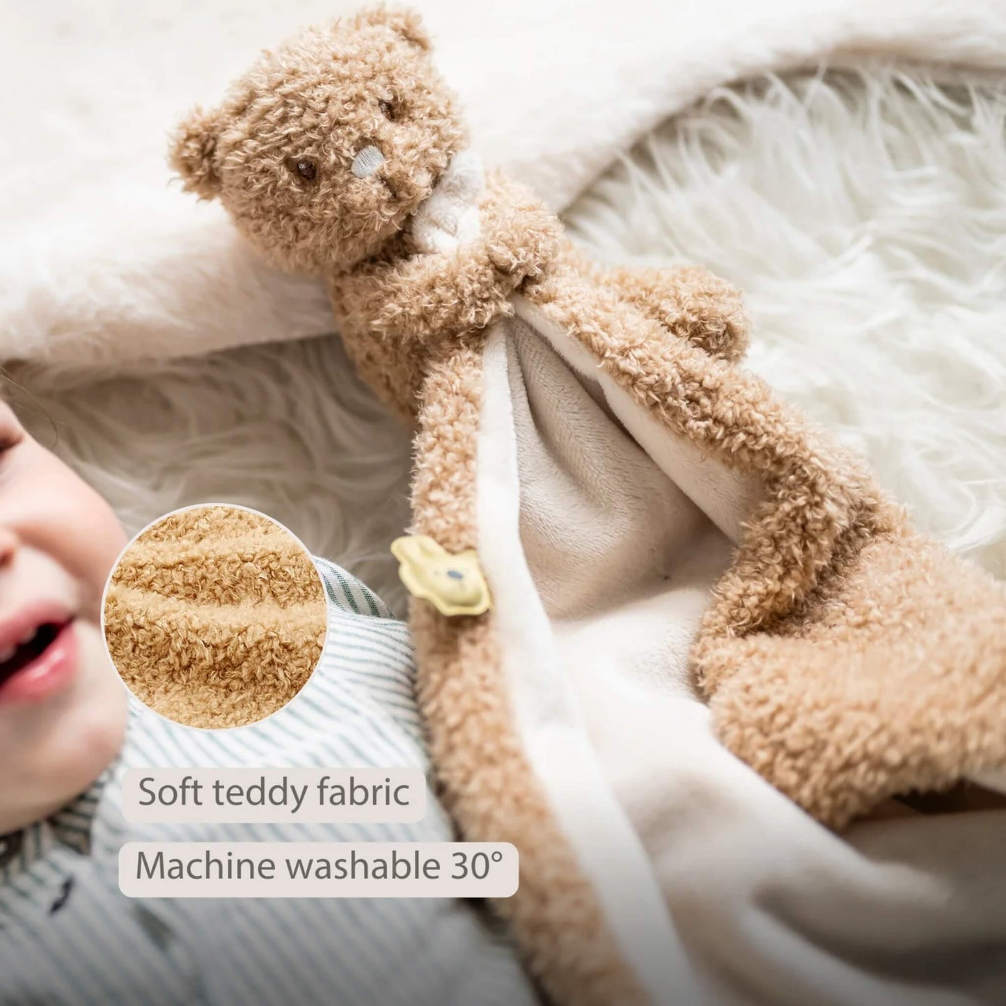 Plush bear baby comforter resting on a soft surface with a close-up circle showing the teddy fabric texture, displayed with the text ‘Soft teddy fabric’ and ‘Machine washable 30°’ on the image.