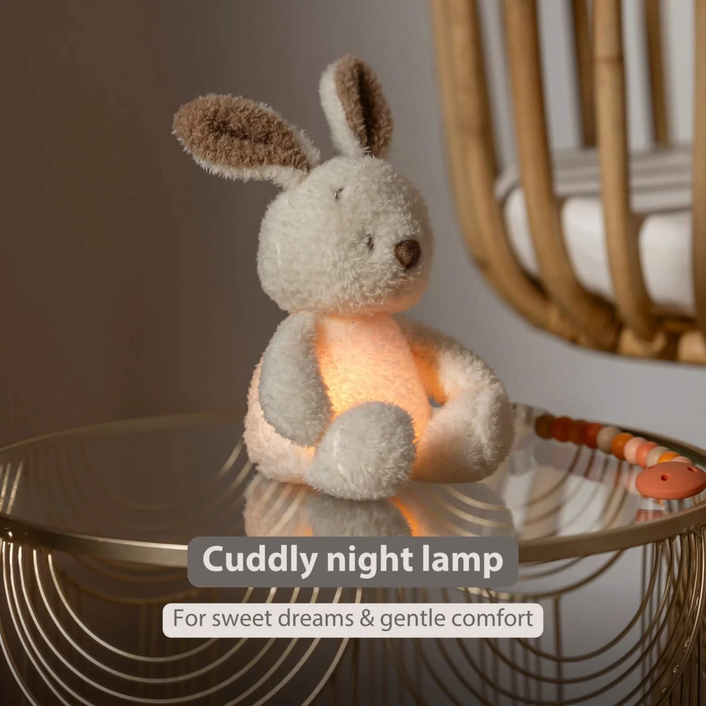 A plush bunny nightlight resting on a bedside table with a gentle warm glow shining through its body.
