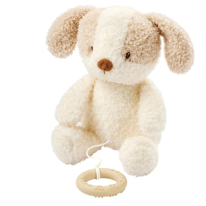 A Nattou Teddy Musical Toy in the Baby Dog design is shown sitting upright, made from soft plush fabric with floppy ears and a silicone pull ring hanging from a short cord.