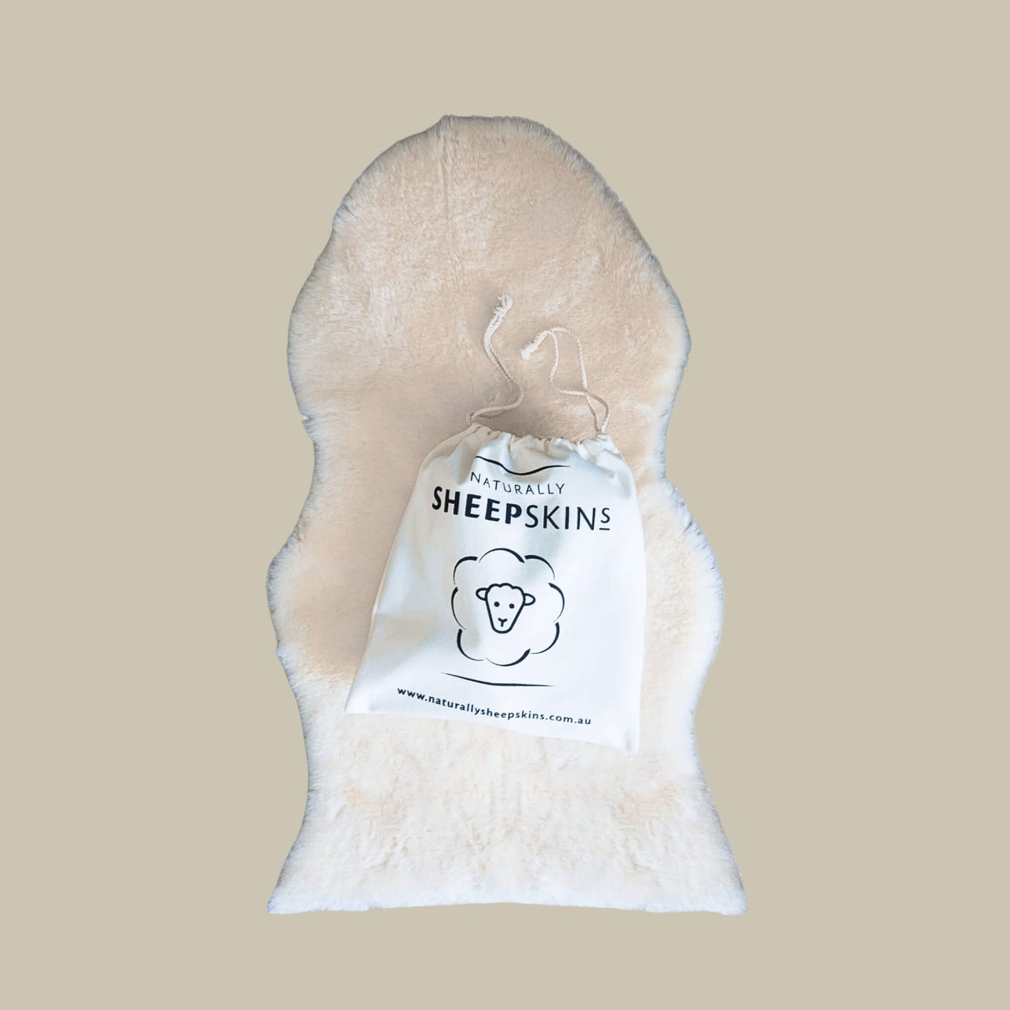 Baby rug in cream colour with drawstring storage bag placed on top, printed with the brand name and sheep logo.