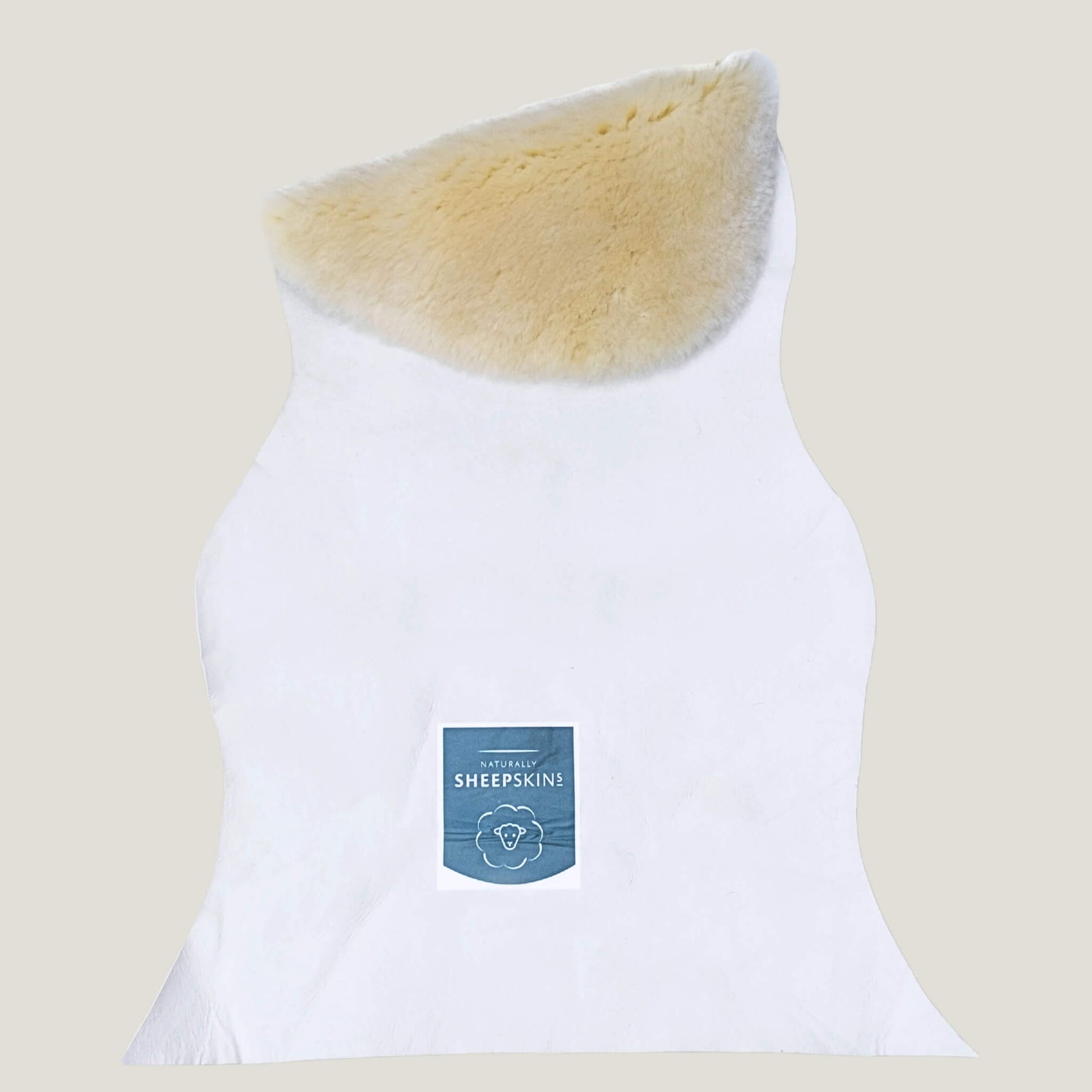 Back of a sheepskin baby rug showing natural white leather underside with product label attached, fleece edge visible at the top.