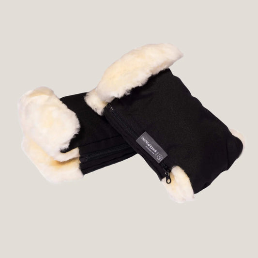 Naturally Sheepskins Stroller Hand Mittens shown in black with soft cream Merino sheepskin lining, zipped design and branded fabric label on the side.