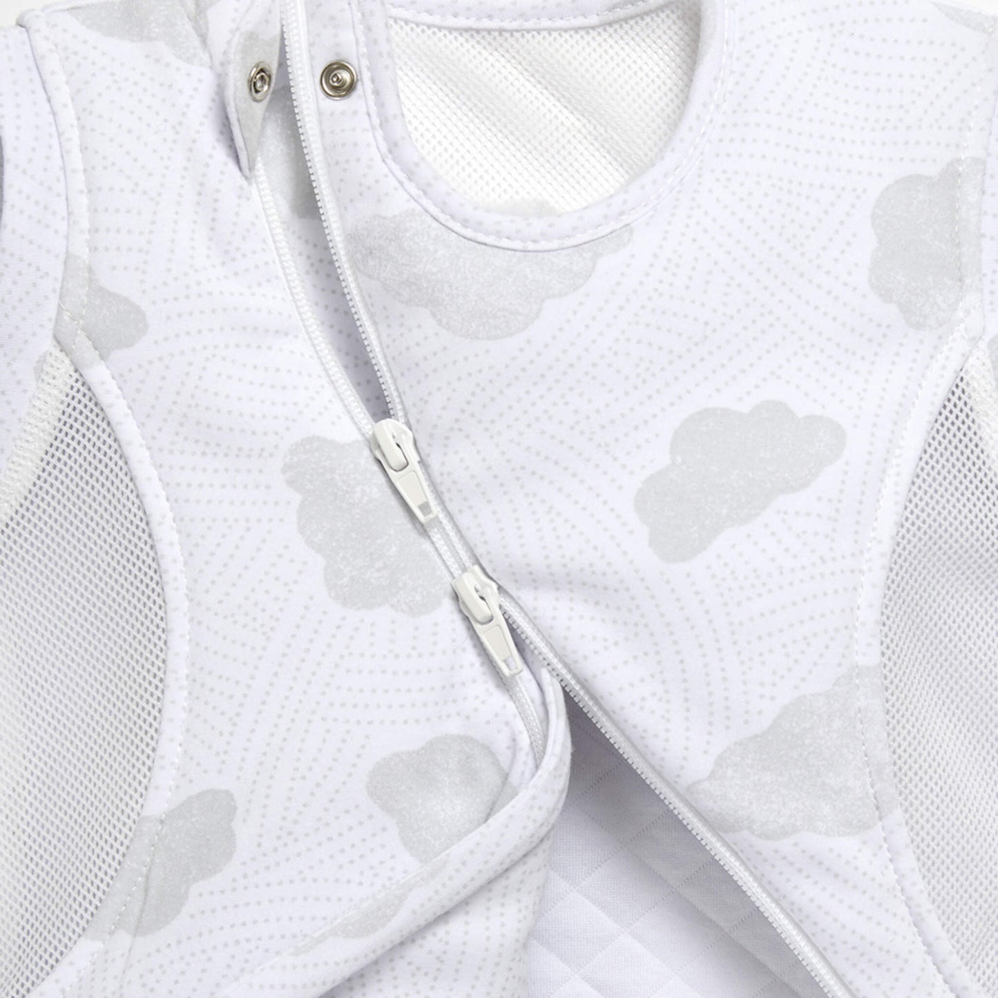 A detailed view of two front zips on a sleep bag, showing how the curved fastening opens across the cloud-patterned fabric.